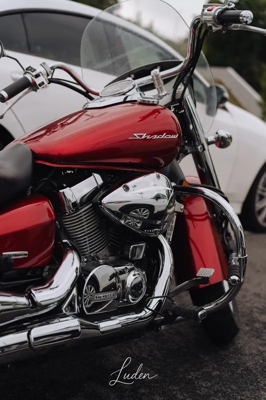 Une moto rouge aux chromes brillants, garée dans la rue.